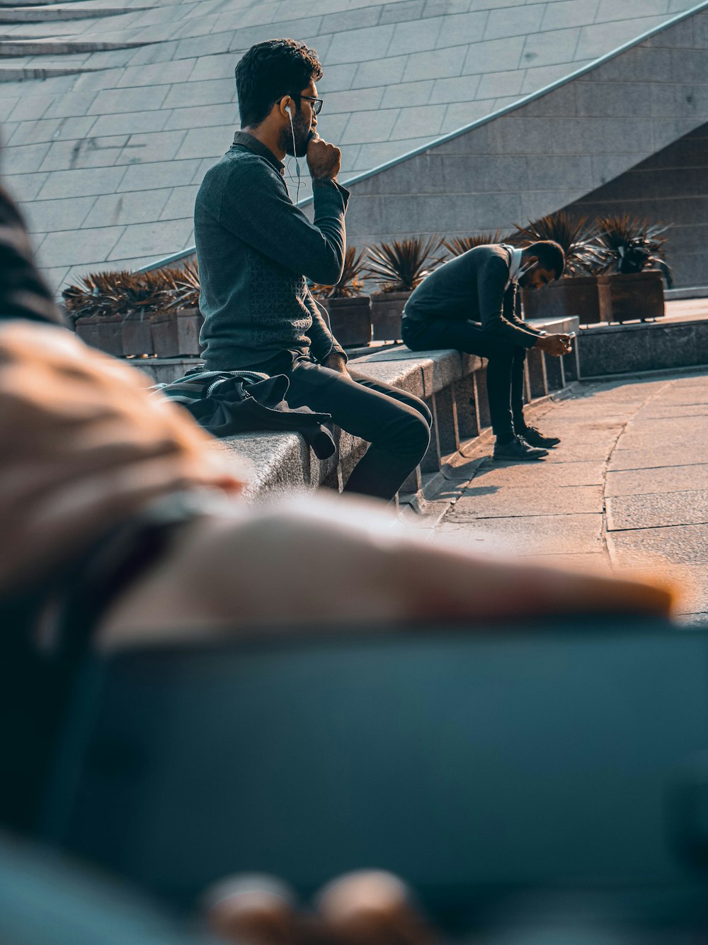 man in black jacket sitting on brown wooden bench during daytime