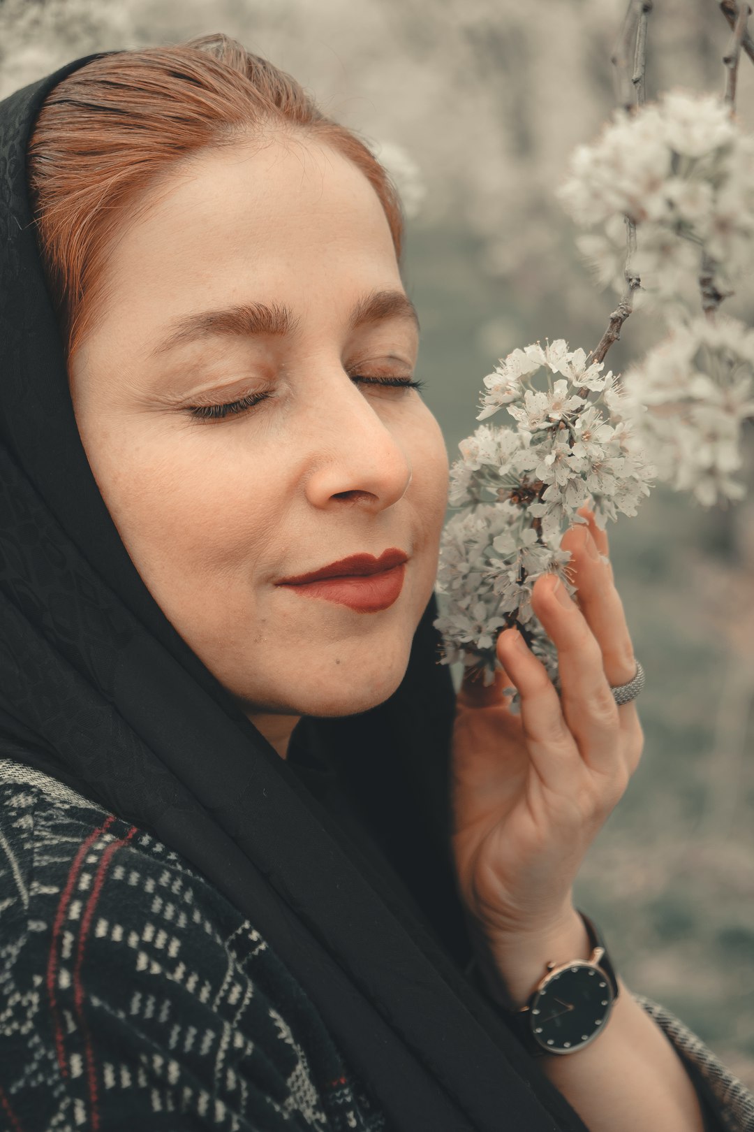 woman in black hijab holding white flowers