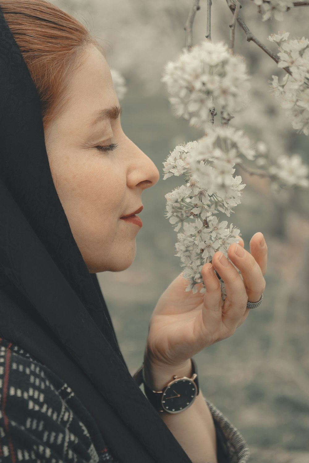woman in black hijab holding white flower