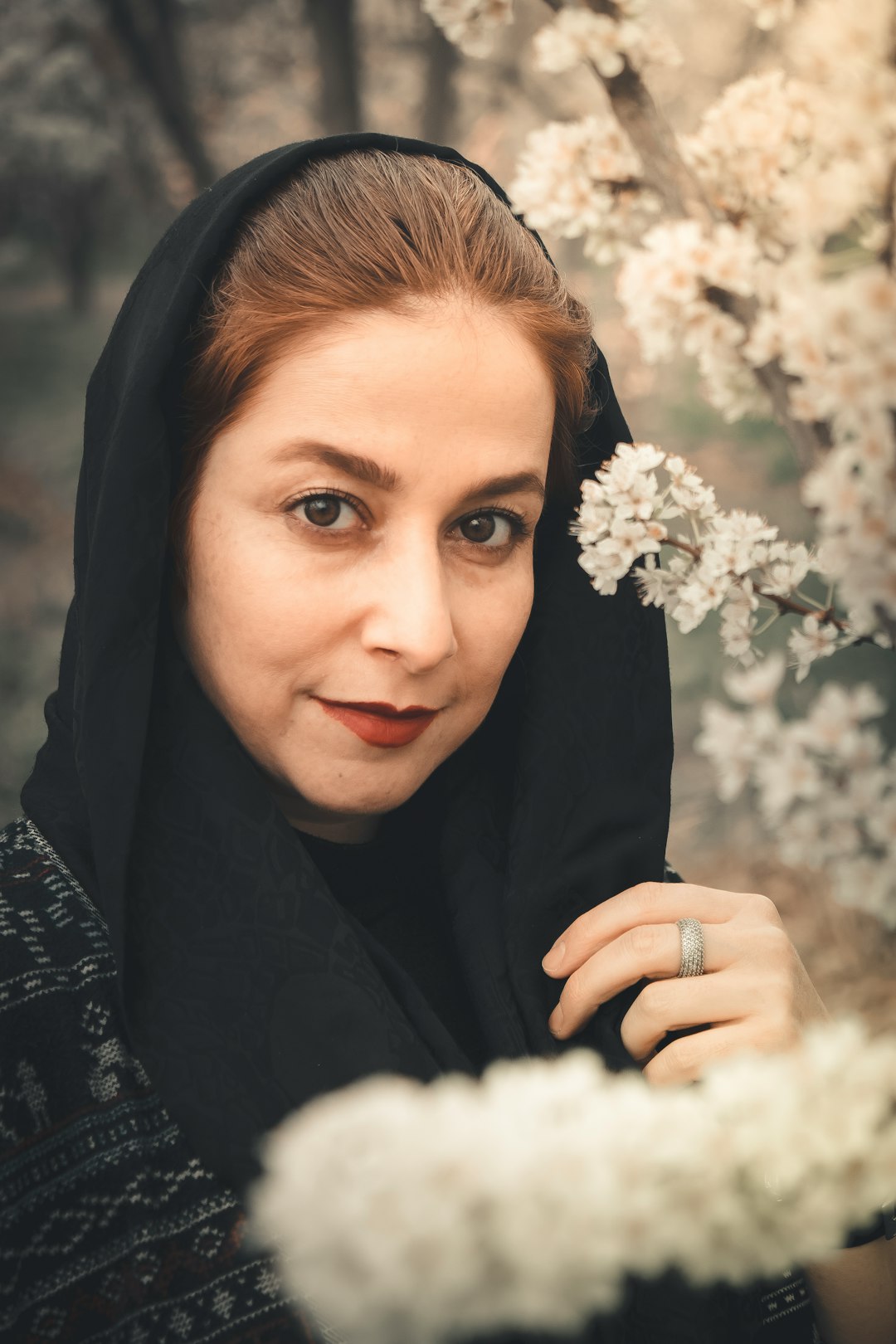 woman in black hijab holding white flowers