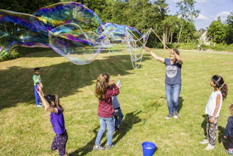 Kids enjoying outdoor toys like colorful balls and bubble wands in a sunny backyard