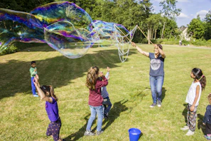 Kids enjoying outdoor toys like colorful balls and bubble wands in a sunny backyard