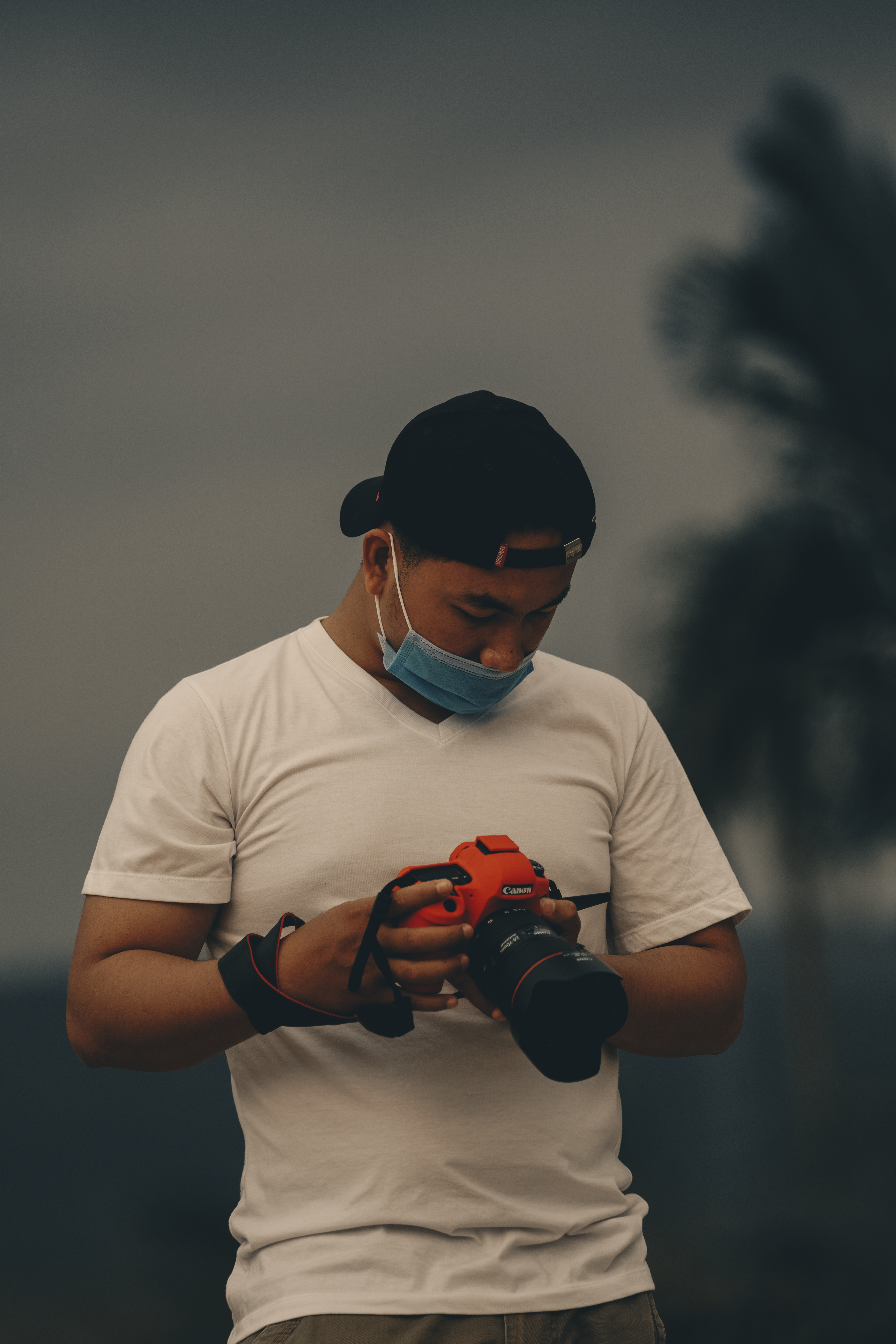 Hombre con camiseta blanca de cuello redondo sosteniendo una cámara DSLR negra
