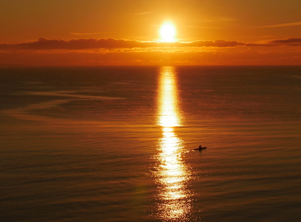 silhouette of person on sea during sunset