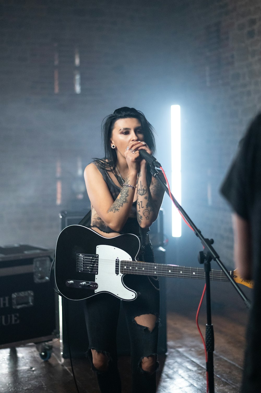 woman in black tank top singing on stage