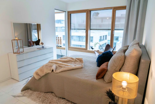 Cozy bedroom with minimalist decor and large window in managed apartment