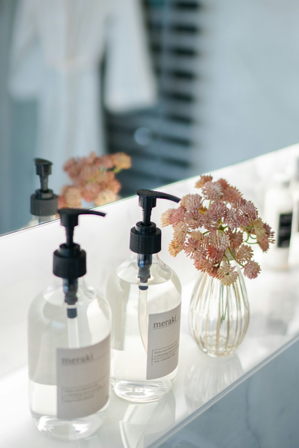 white and brown flowers in clear glass bottles