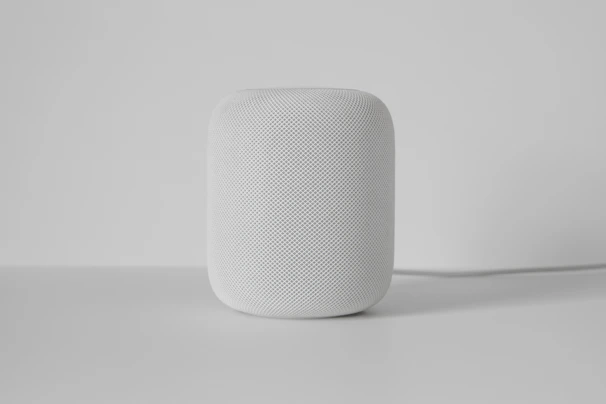 A sleek smart home device glowing softly on a minimalist white shelf