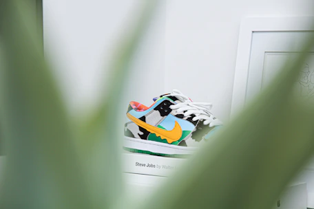 A vibrant display of eco-friendly sports shoes in green and blue tones on a rustic wooden shelf.