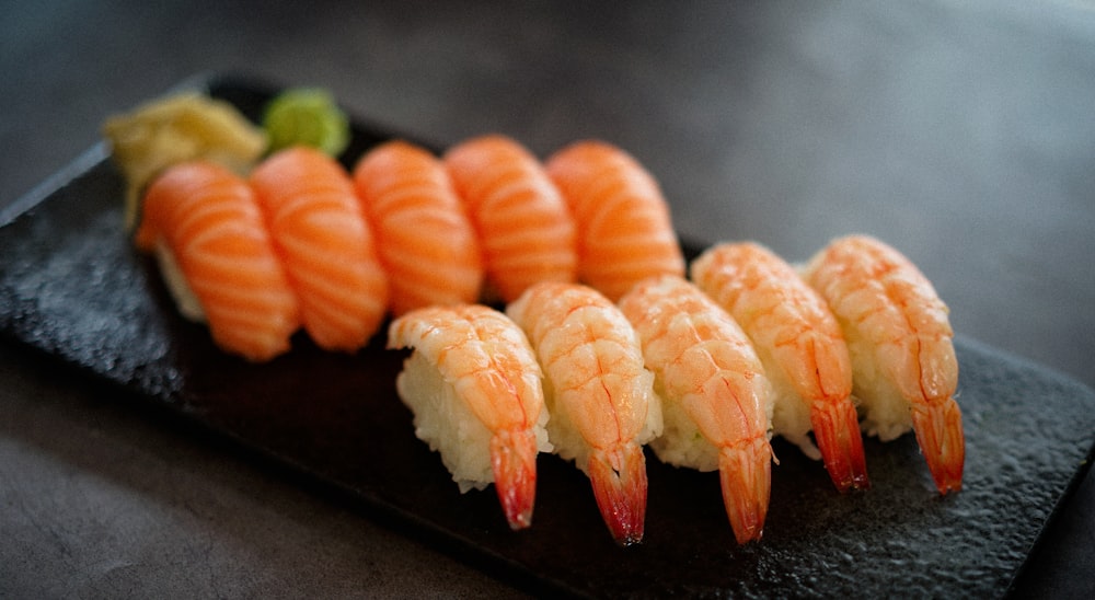 orange and white sushi on black tray