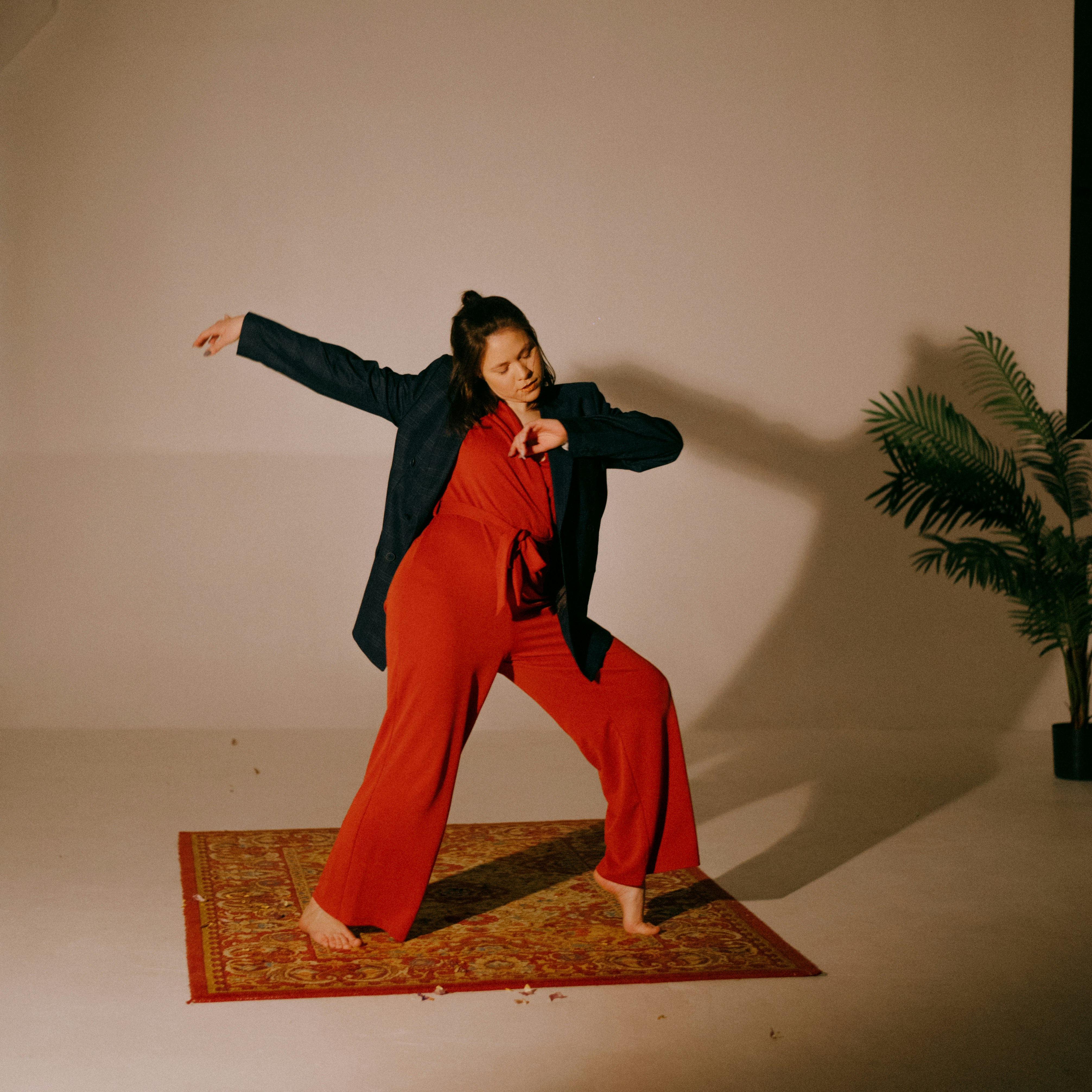 woman in black long sleeve shirt and red pants standing on brown wooden seat