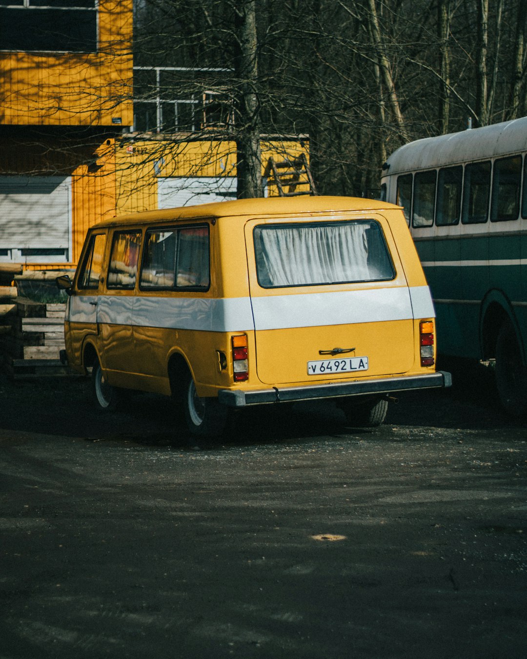 blue and white van parked beside yellow and white concrete building during daytime