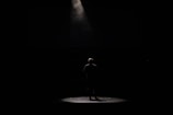 A dramatic spotlight shining on a solo dancer surrounded by shadows.