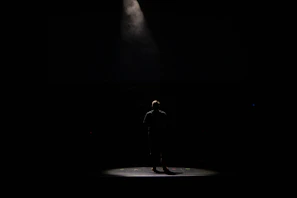 A black-and-white photo of an actor rehearsing a dramatic monologue under a single spotlight on stage.