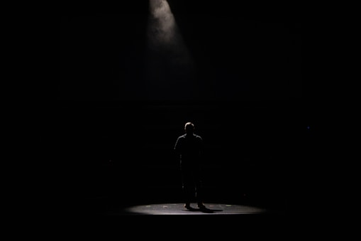 Binoy Cherian performing a dramatic monologue under warm stage lighting.