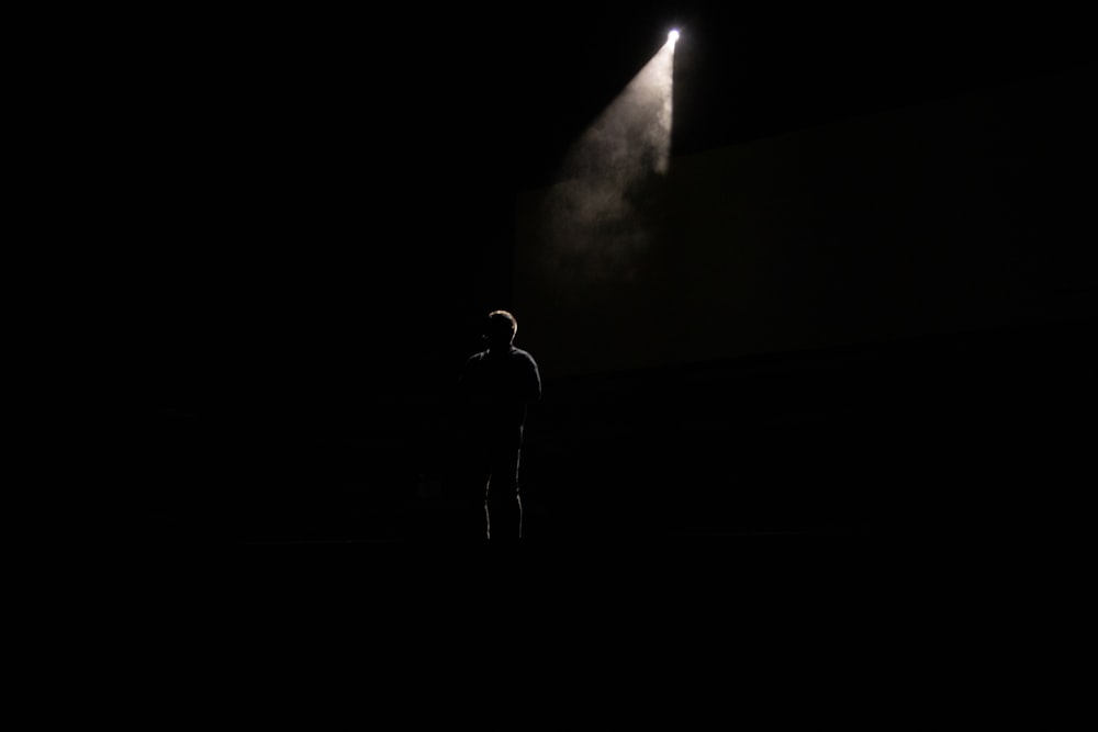 silhouette di persona in piedi sul palco