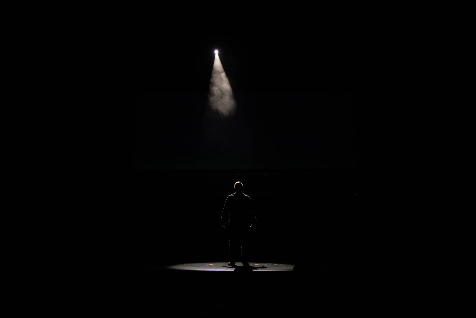A single spotlight on an empty dark stage, representing the narrow selection AI systems make when choosing what to cite
