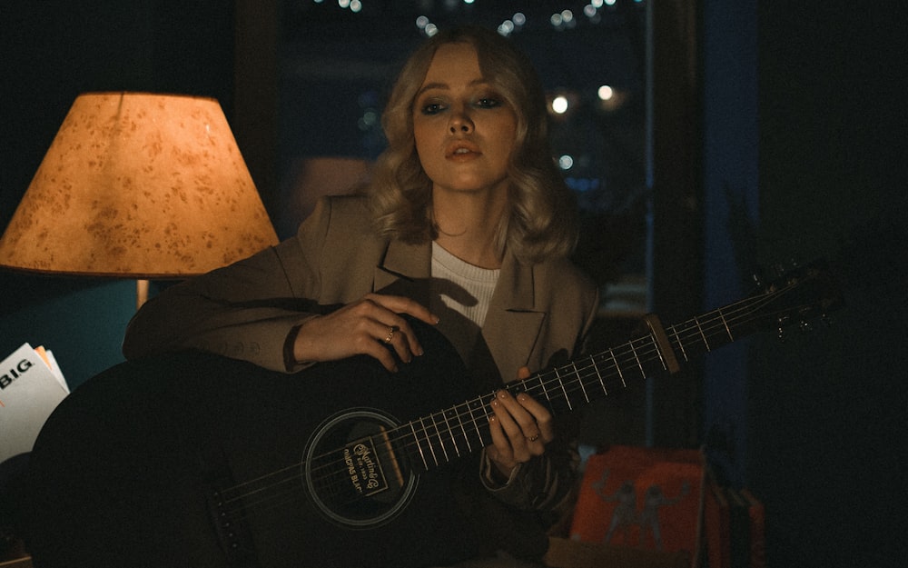 woman in black blazer playing acoustic guitar