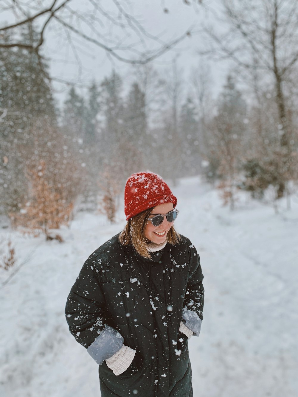 a woman standing in the snow wearing a red hat