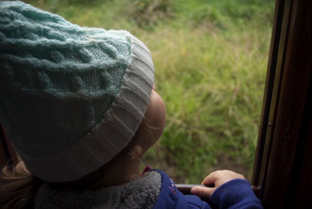 child in blue jacket and white knit cap