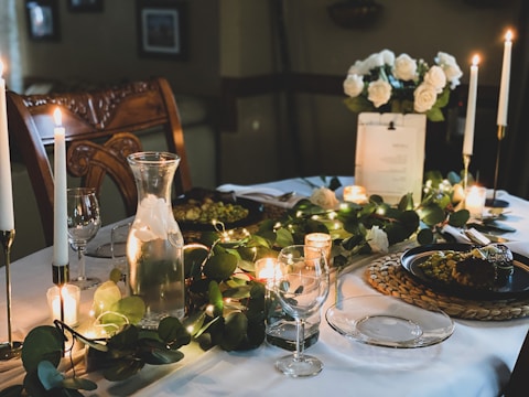 An intimate table setting with simple greenery garlands and soft candlelight glowing in the evening.