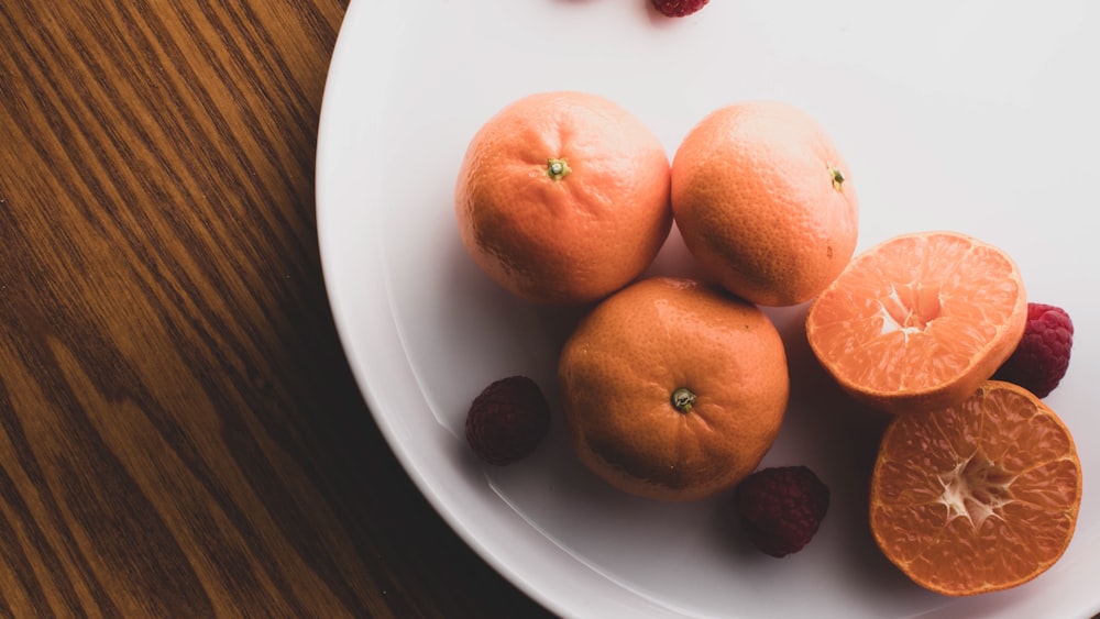 three orange fruits on white ceramic plate