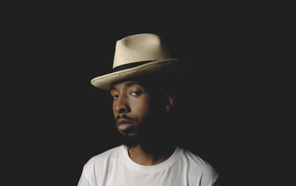 man in white crew neck shirt wearing brown fedora hat