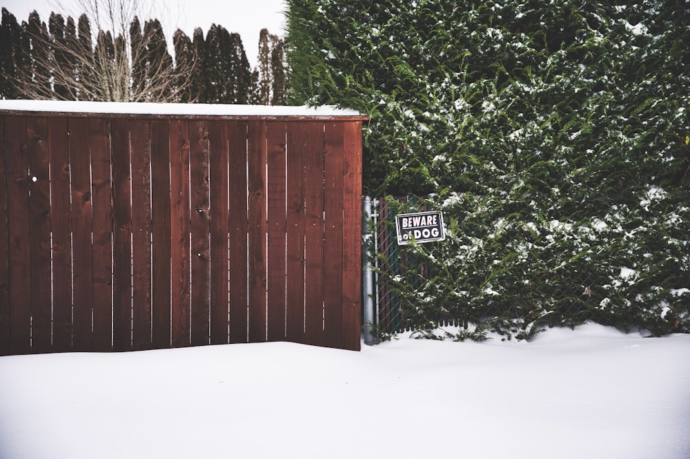 staccionata in legno marrone ricoperta di neve