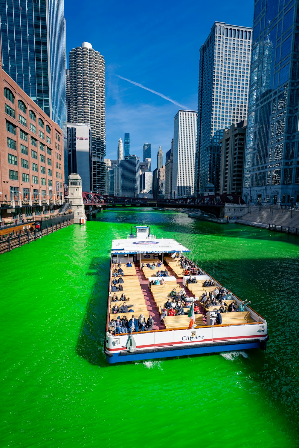 people riding on white and blue boat on river between high rise buildings during daytime