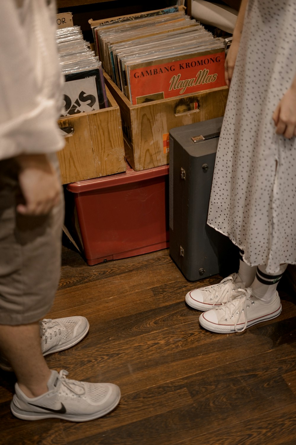 person in white pants and white sneakers standing on brown wooden parquet floor