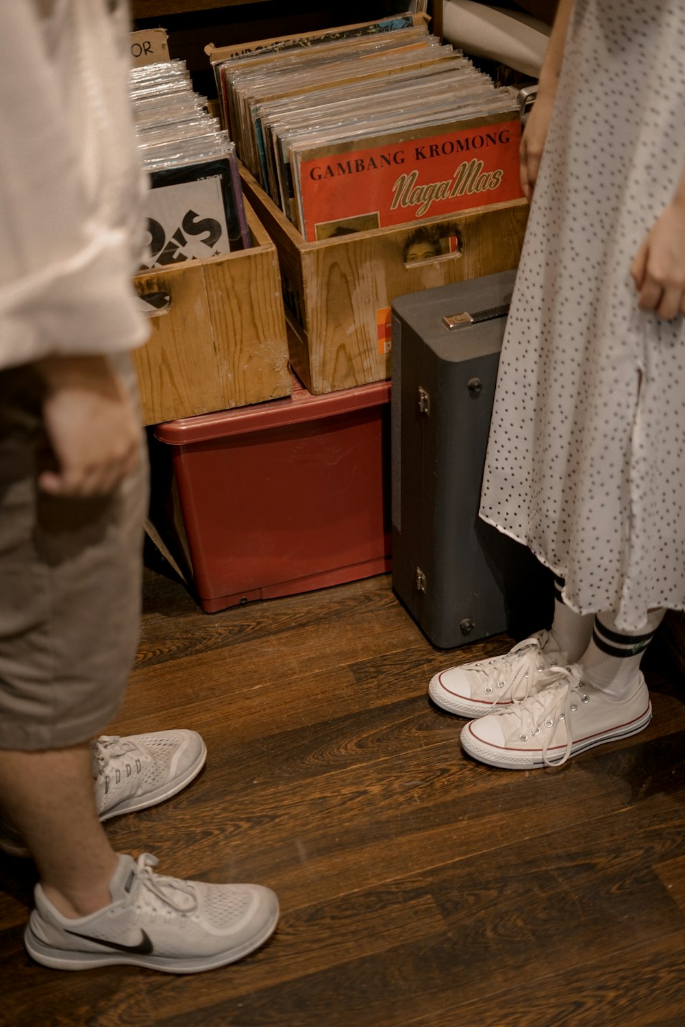 persona in pantaloni bianchi e scarpe da ginnastica bianche in piedi sul pavimento in parquet di legno marrone