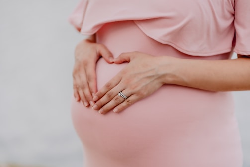 femme enceinte avec une robe rose posant les mains sur son ventre