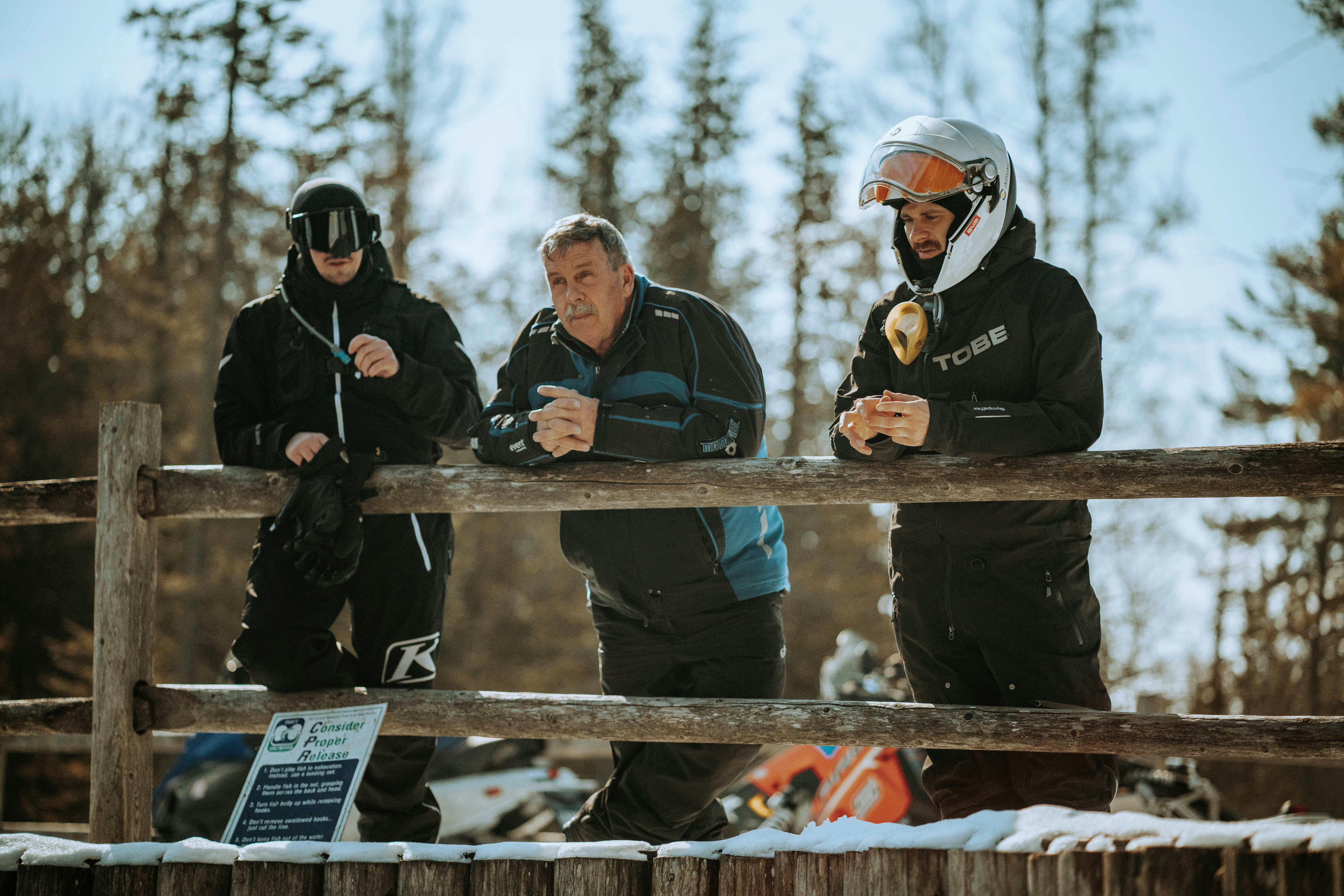 man in black jacket standing beside man in black jacket, Man with blue and black winter jacket talking to friends.