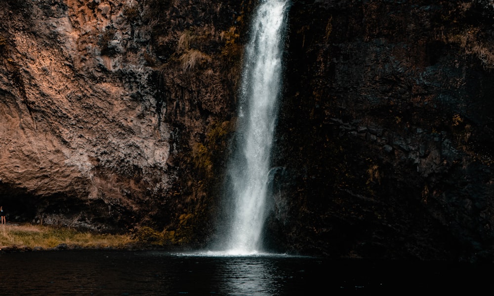 water falls on brown rocky mountain