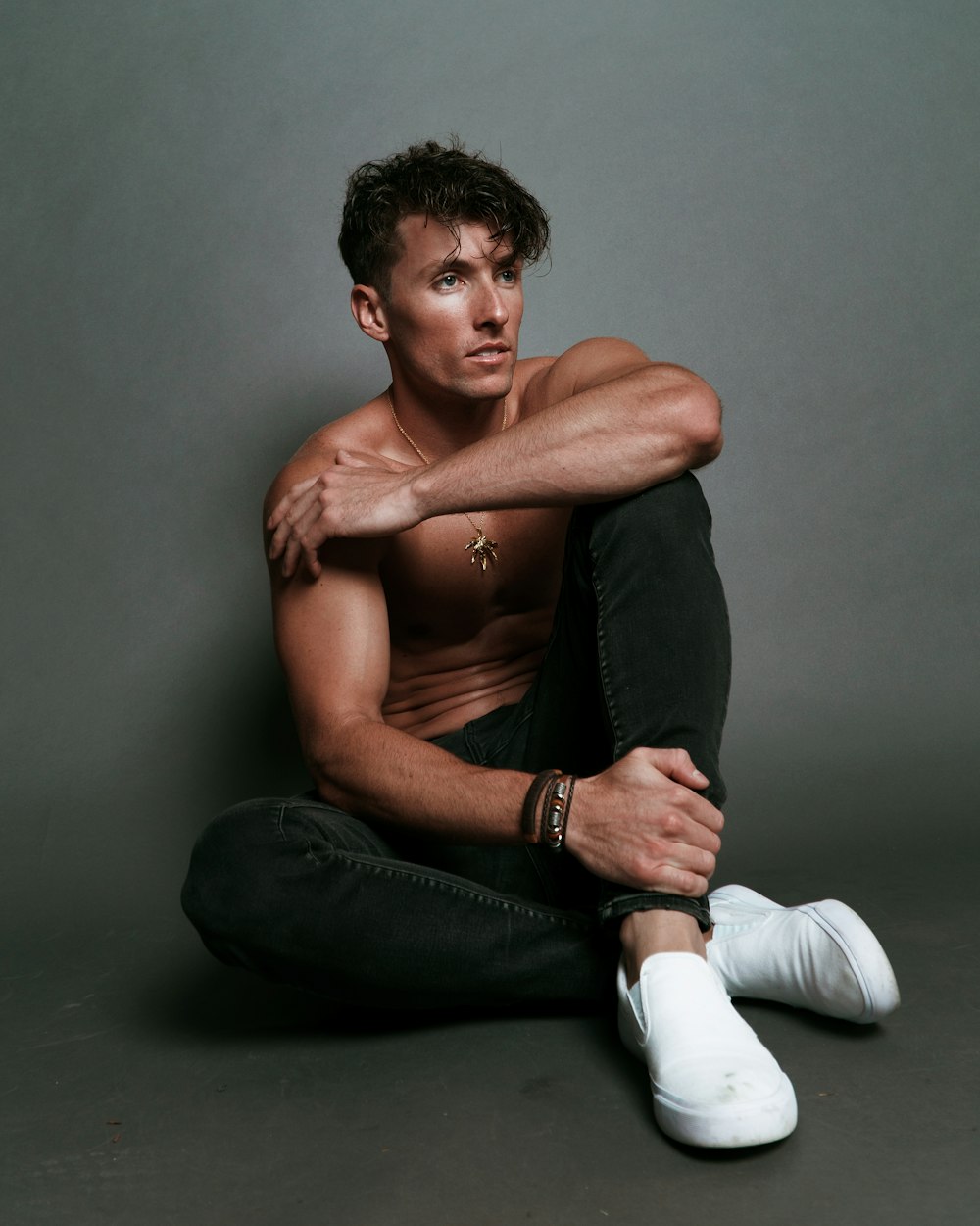topless man in black pants and white socks sitting on black textile