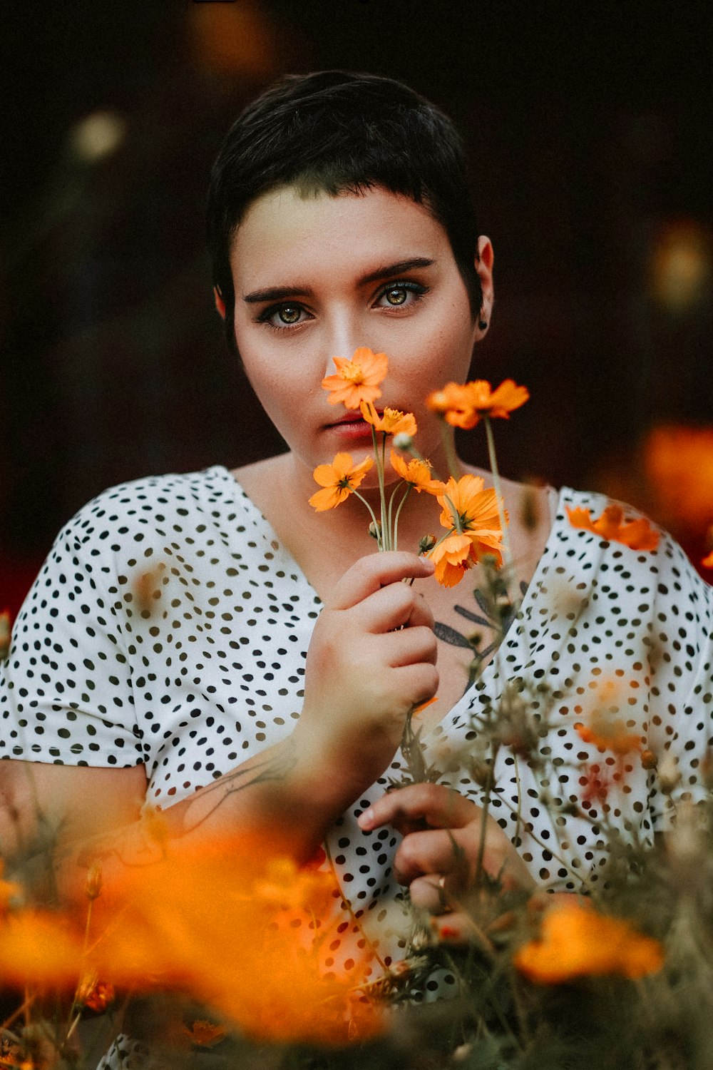 woman in white and brown floral shirt holding yellow flowers