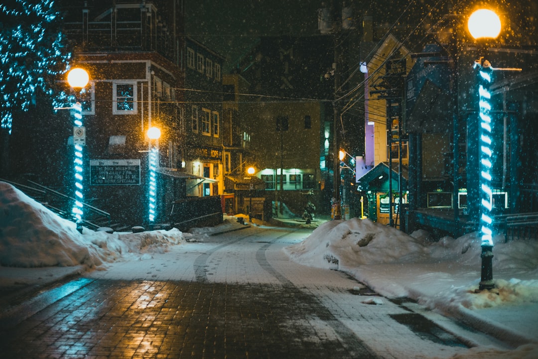 snow covered road between buildings during night time