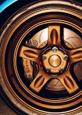 A close-up view of a car's bronze alloy wheel with intricate design detailing and visible brake components, including a Brembo brake caliper.