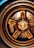 A close-up view of a car's bronze alloy wheel with intricate design detailing and visible brake components, including a Brembo brake caliper.