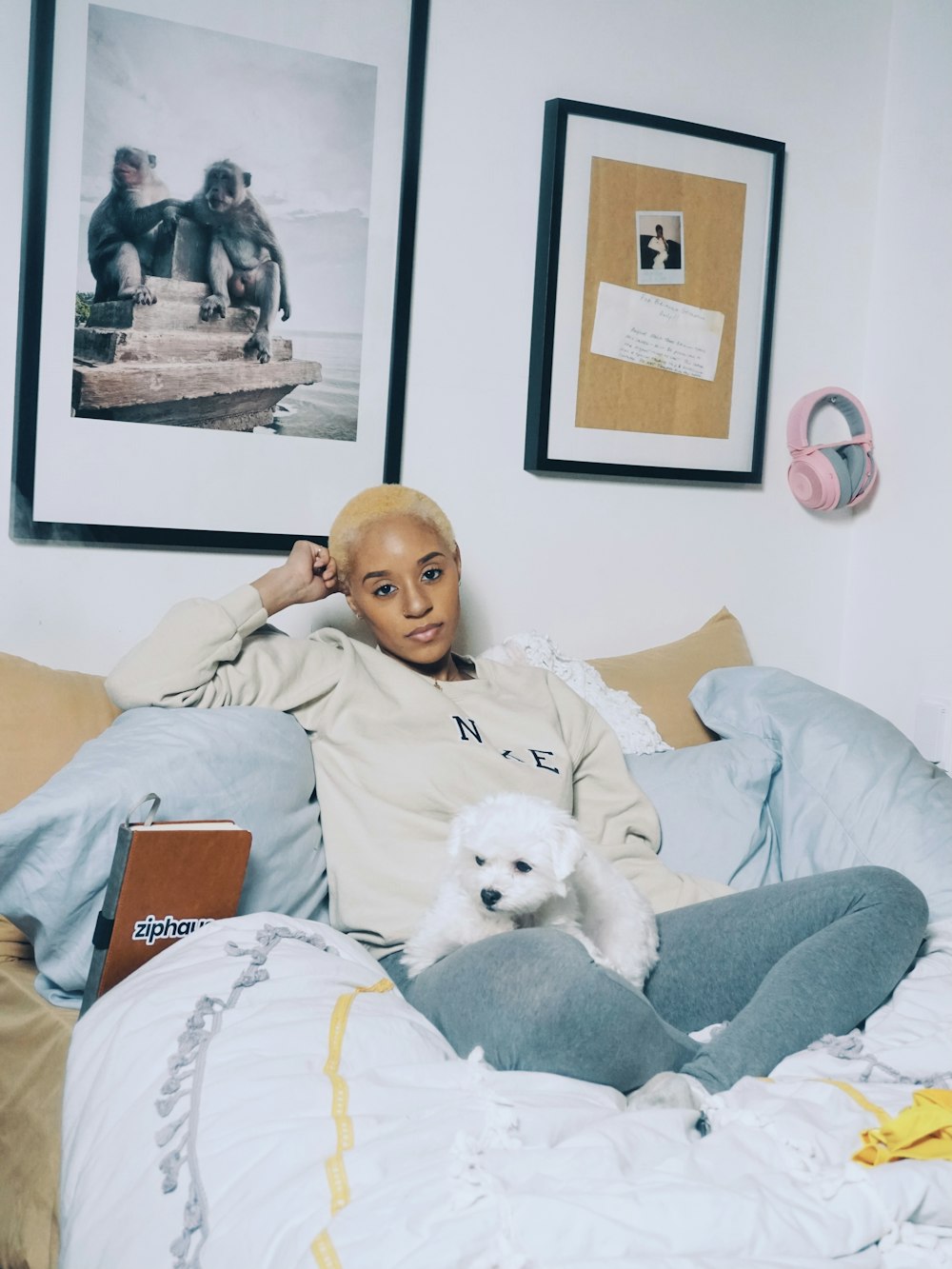 woman in gray long sleeve shirt lying on bed beside white dog