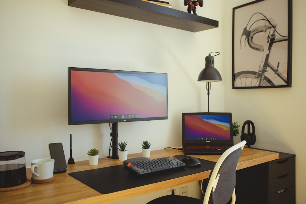 black flat screen computer monitor turned on beside black computer keyboard on brown wooden desk