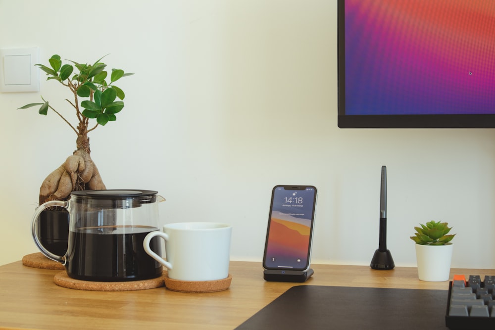 black iphone 7 beside white ceramic mug on brown wooden table