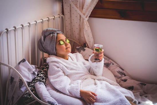 baby in white sweater and yellow goggles lying on bed