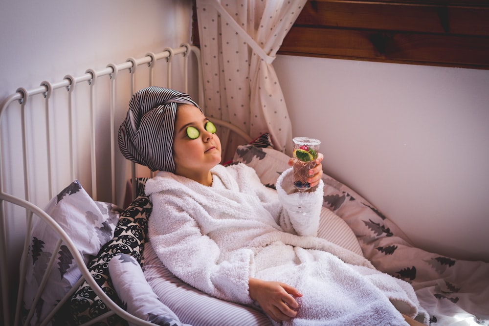 baby in white sweater and yellow goggles lying on bed