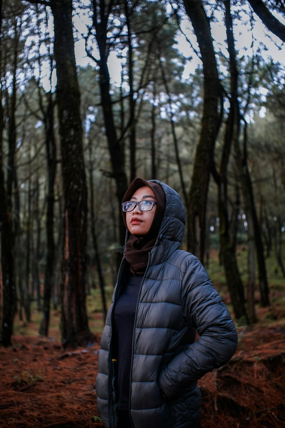 woman in black bubble jacket standing in forest during daytime