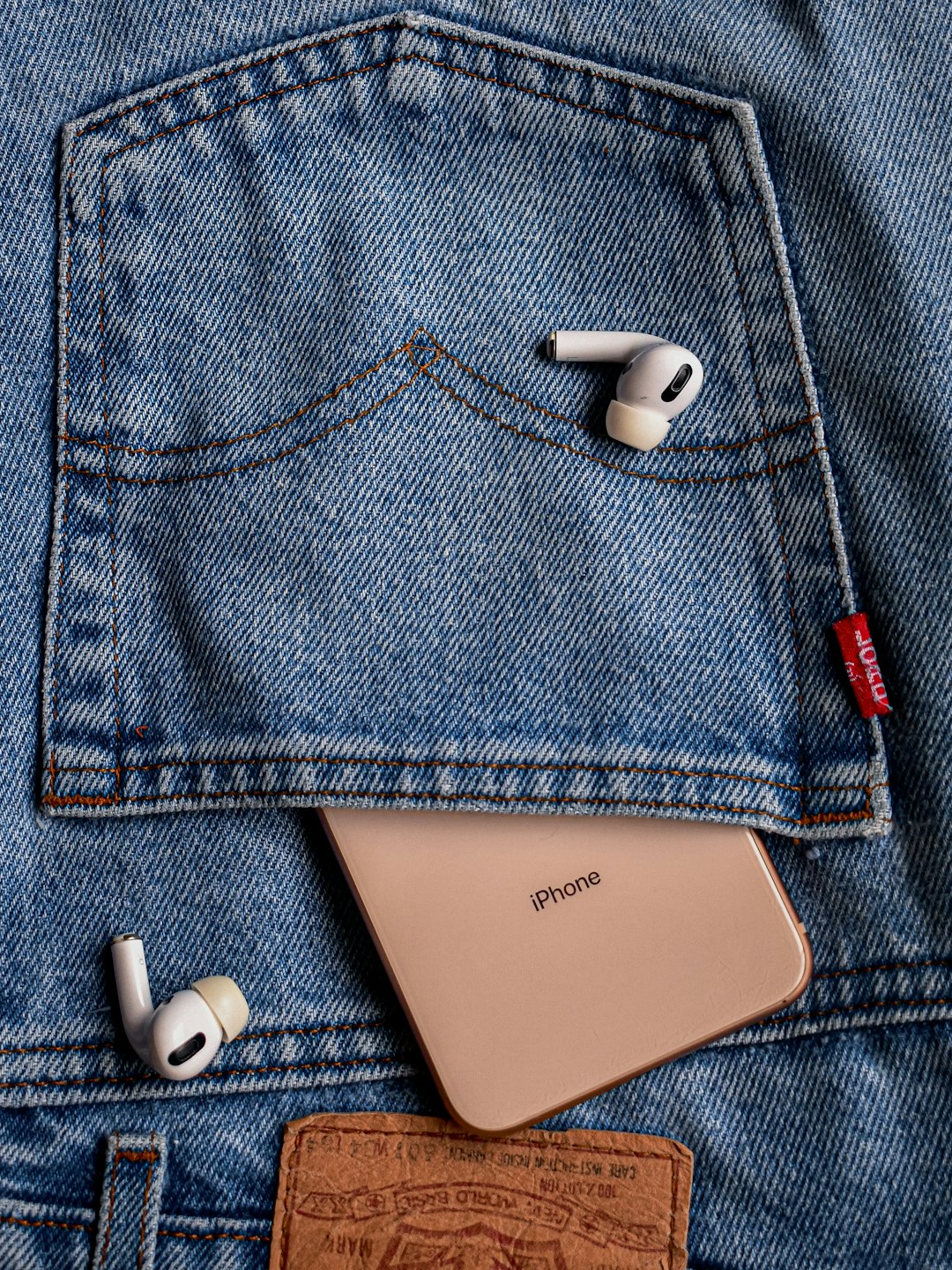 white earbuds on blue denim jeans