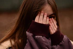 woman in purple sweater covering her face
