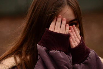 woman in purple sweater covering her face