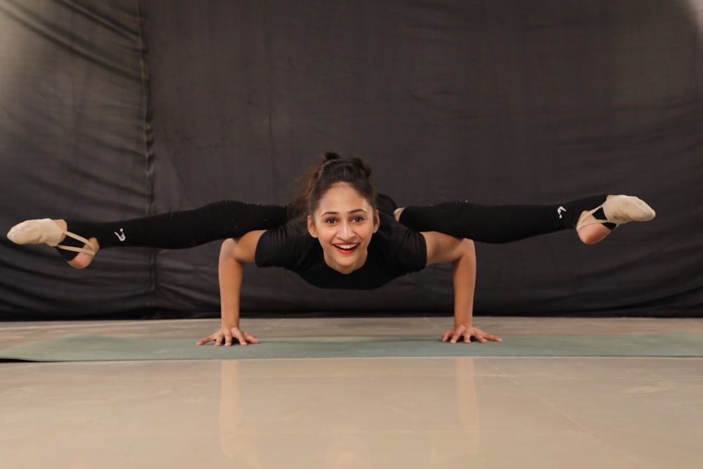 Mujer con camiseta negra y pantalones negros haciendo yoga