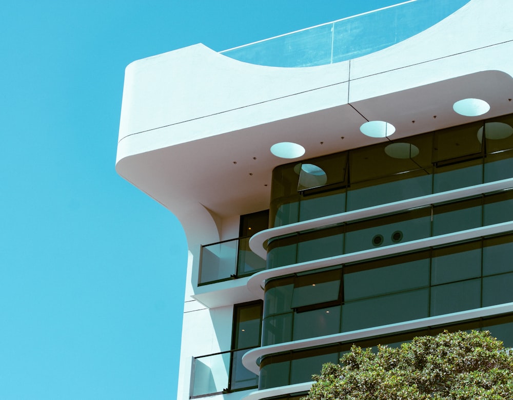 white concrete building near green tree under blue sky during daytime